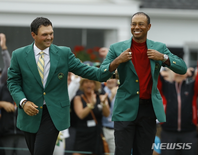 Patrick Reed helps Tiger Woods with his green jacket after Woods won the Masters golf tournament Sunday, April 14, 2019, in Augusta, Ga. (AP Photo/Matt Slocum)