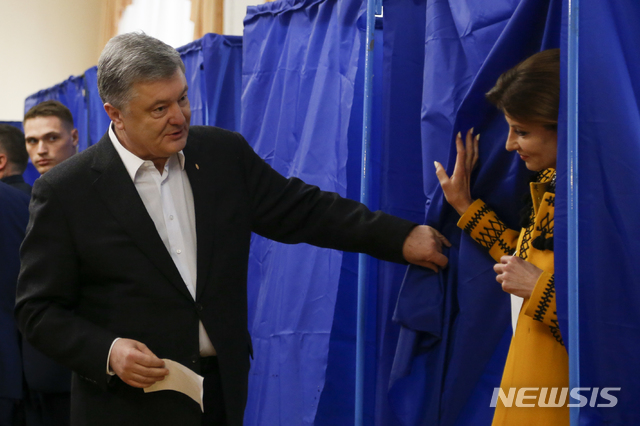 【키에프=AP/뉴시스】 우크라이나의 페트로 포로셴코 대통령이 21일(현지시간) 대선 결선투표 투표장에서 부인 마리나 여사가 기표소에서 나오는 것을 도와주고 있다. 2019.04.22.