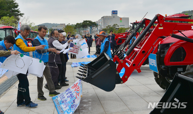 【무안=뉴시스】변재훈 기자 = 6·15공동선언실천 남측위원회 전남본부와 전국농민회 광주·전남연맹이 25일 오전 전남 무안군 삼향읍 전남도청 앞에서 4·27판문점선언 1주년 기념식과 통일트랙터 방북 출정식을 열고 있다. 행사가 끝난 뒤 트랙터 로더로 대북제재와 군사분계선을 상징하는 철조망을 들어올리는 퍼포먼스가 펼쳐지고 있다. 2019.04.25.  wisdom21@newsis.com