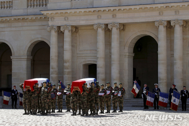 Special forces soldiers carry the coffins of the late special forces soldiers Cedric de Pierrepont and Alain Bertoncello, who were killed in a night-time rescue of four foreign hostages including two French citizens in Burkina Faso last week, during a national tribute at the Invalides, in Paris, Tuesday, May 14, 2019. France is honoring two special forces officers killed in an operation that freed four hostages held in Burkina Faso. (Philippe Wojazer/Pool via AP)