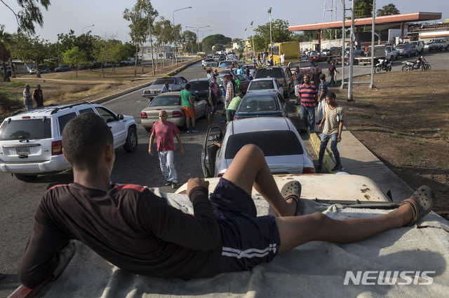 【카라카스 = AP/뉴시스】 주유소 앞 대기 차량의 지붕에서 잠을 청하는 시민들 