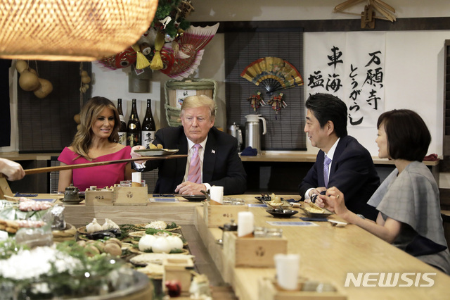 U.S. President Donald Trump, second left, is served a baked potato with butter while sitting at a counter with first lady Melania Trump, second left, Japan&#039;s Prime Minister Shinzo Abe, second right, and his wife Akie Abe during a dinner at the Inakaya restaurant in the Roppongi district of Tokyo, Sunday, May 26, 2019. (Kiyoshi Ota/Pool Photo via AP)