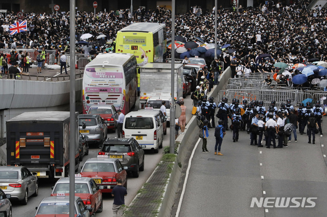  【홍콩=AP/뉴시스】12일(현지시간) 홍콩 입법회의 인근 봉쇄된 도로에서 시위 진압 경찰이 시위대와 대치하고 있다.  홍콩 입법회의는 중국과의 범인 인도 협정 개정을 위한 2차 법률 심의를 벌일 예정인 가운데 시민 수천 명은 오전부터 입법회의로 가는 길목인 렁우가를 점거하고 시위를 벌이고 있다. 2019.06.12.  