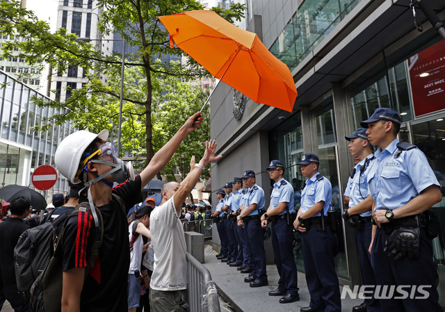 【홍콩=AP/뉴시스】21일(현지시간) 홍콩 경찰본부 앞에서 범죄인 인도법안반대 시위를 벌이던 한 남성이 경찰을 향해 우산을 들어 보이고 있다. 주로 학생으로 구성된 수백 명의 시위대는 범죄인 인도법안의 완전 철회를 요구하며 정부청사 앞에 다시 모여들었다. 2019.06.21.