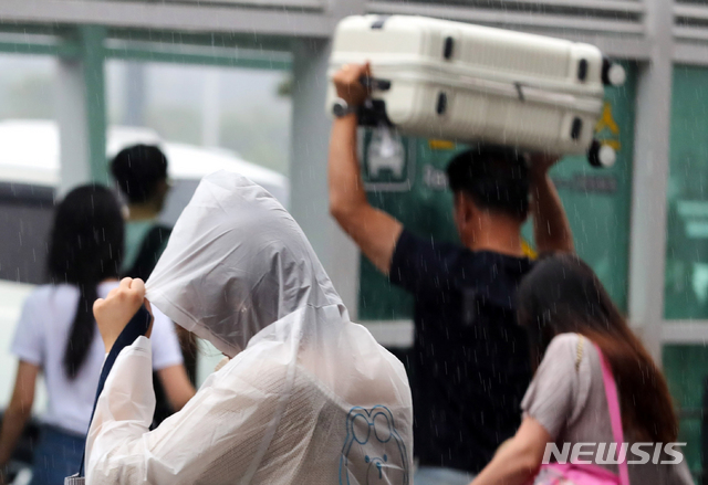 [제주=뉴시스]우장호 기자 = 제주국제공항 이용객들이 비를 피하며 발걸음을 재촉하고 있다. (뉴시스DB) woo1223@newsis.com