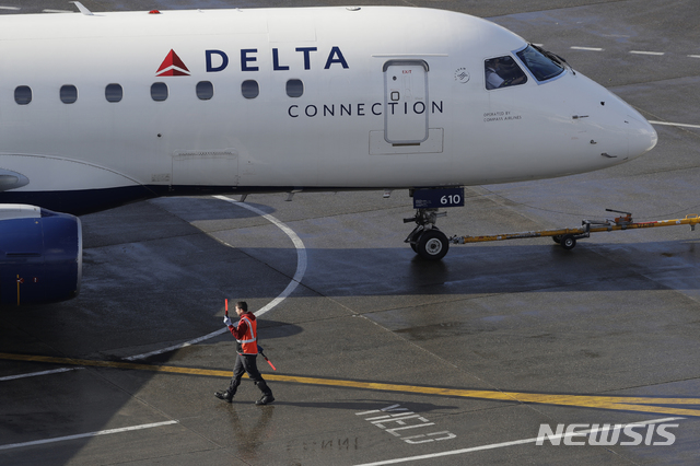 [시애틀=AP/뉴시스] 지난해 2월5일(현지시간) 미국 워싱턴주 시애틀의 시애틀-터코마 국제공항에서 한 근무자가 델타 항공기를 안내하고 있다. 2020.10.26.
