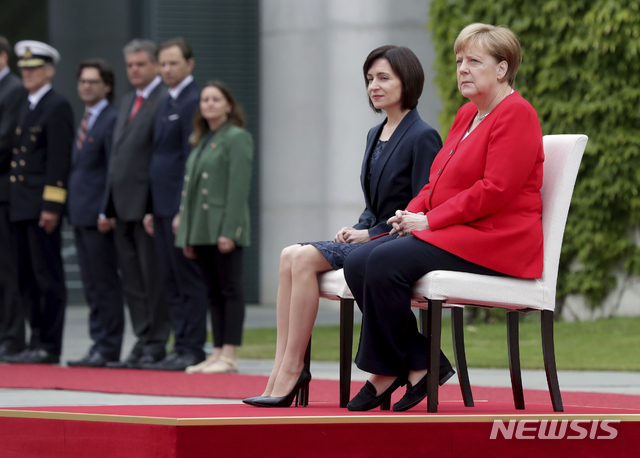 【베를린=AP/뉴시스】 독일의 앙겔라 메르켈 총리(오른쪽)가 16일 몰도바의 마이아 산두 총리의 예방을 받고 총리 관저 실외에서 의자에 앉아 의장대 환영 의식을 지켜보고 있다. 지난달 18일 이후 서 있는 공개 석상에서 세 번이나 건강에 이상이 있는 듯 몸을 심하게 떨었던 메르켈은 사흘 전 덴마크 신임 총리의 환영식 때부터 의자에 앉아 시종 환영식 행사를 치르고 있다 