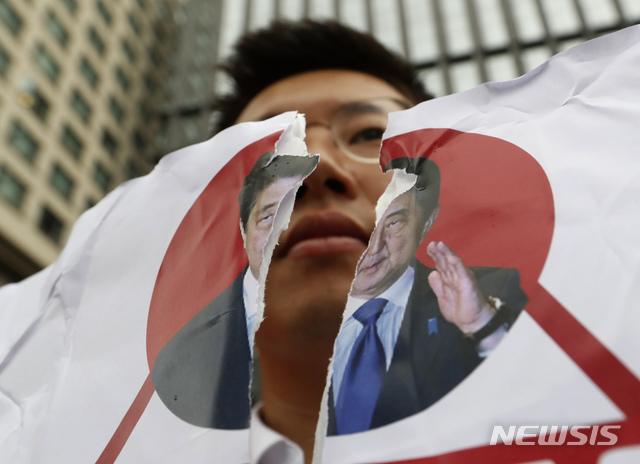 【서울=AP/뉴시스】17일 한국 서울의 일본 대사관 앞에서 한 시위 참가자가 아베 신조 일본 총리의 찢긴 사진을 들고 있다. 2019.07.23.