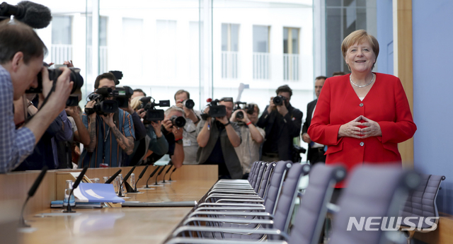 메르켈 총리가 19일 여름 휴가 전 기자회견장에 밝은 표정으로 들어서고 있다  AP