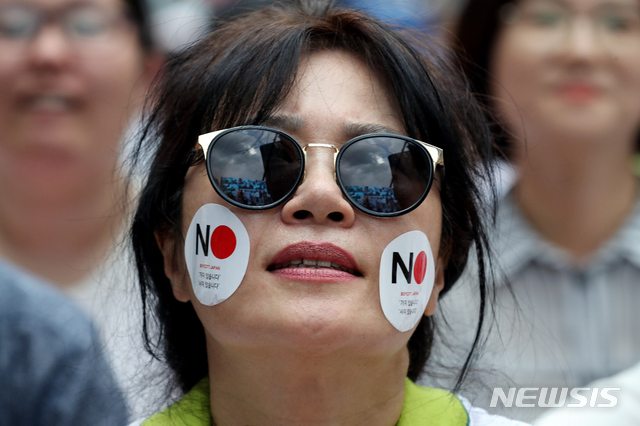 【서울=뉴시스】김병문 기자 = 일본의 화이트리스트 제외 결정 다음 날인 3일 오후 서울 종로구 일본대사관 앞에서 역사왜곡·경제침략·평화위협 아베규탄 시민행동(아베규탄시민행동) 주최로 열린 ‘아베 규탄 3차 촛불문화제’에 참석한 시민이 얼굴에 반일 스티커를 붙이고 있다. 2019.08.03.  dadazon@newsis.com