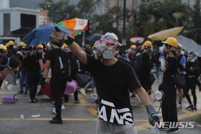 【홍콩=AP/뉴시스】총파업으로 교통 등이 마비된 홍콩에서 5일 경찰과 대치 중인 시위대 속의 남성이 벽돌을 들고 있다. 홍콩에서는 이날 긴 목봉을 휘두르는 흰색 셔츠 차림의 폭도들이 시위대를 공격하는 백색테러가 재현됐다. 2019.8.5