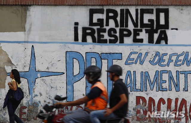【카라카스=AP/뉴시스】6일(현지시간) 베네수엘라 수도 카라카스에서 행인들이 "양키들은 우리를 존중하라"라고 쓰인 벽 앞을 지나고 있다. 