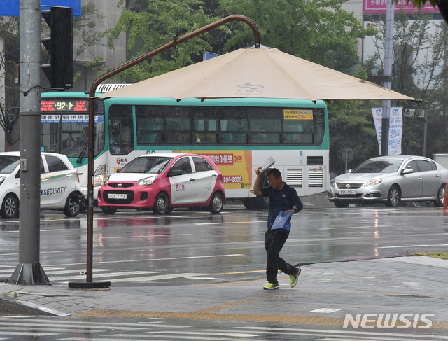 【수원=뉴시스】 김종택 기자 = 제9호 태풍 레끼마가 만들어낸 비구름의 영향으로 전국이 흐리고 비가 내린 지난달 12일 오전 경기도 수원시 팔달구 인계동 횡단보도에 설치된 대형 그늘막 아래 시민들이 비를 피하고 있다. 2019.08.12.semail3778@naver.com