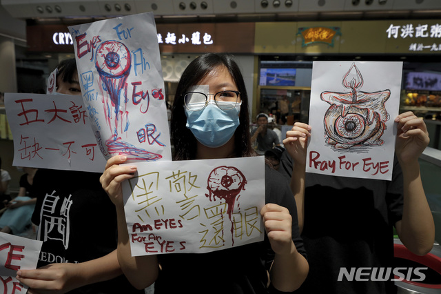 【홍콩=AP/뉴시스】12일(현지시간) 홍콩 국제공항 입국장에서 시위대가 "눈에는 눈" "흑경(나쁜 경찰), 눈 내놔라" 등의 구호가 쓰인 손팻말을 들고 시위를 벌이고 있다.  지난 11일 홍콩 경찰이 고글을 착용한 한 여성 시위자에게 고무탄을 쏴 고글을 깨고 들어간 탄환이 여성을 실명시킨 것으로 전해진 바 있다. 2019.08.12.  