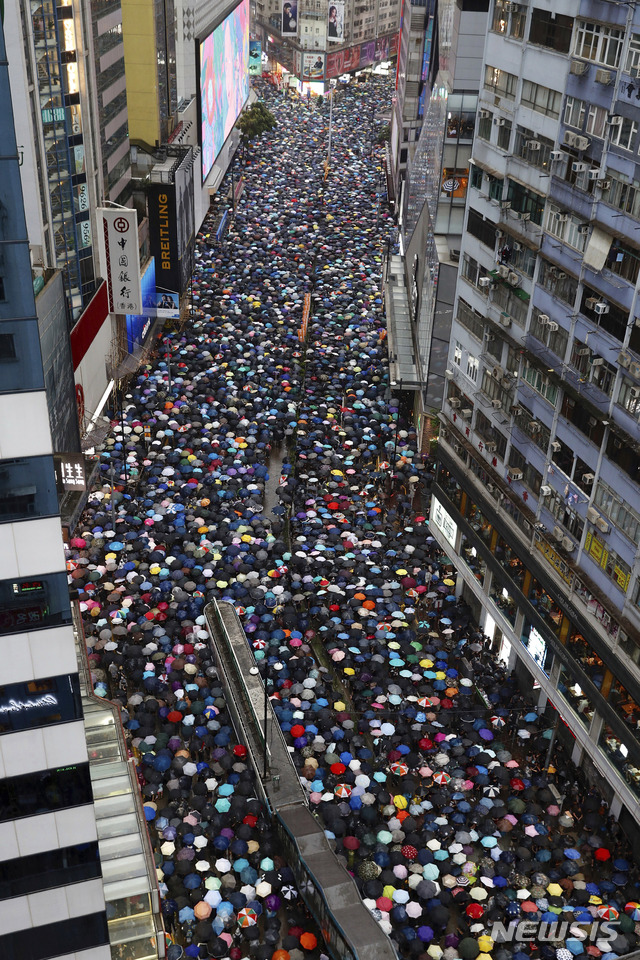 Demonstrators carry umbrellas as they march along a street in Hong Kong, Sunday, Aug. 18, 2019. Heavy rain fell on tens of thousands of umbrella-ready protesters Sunday as they started marching from a packed park in central Hong Kong, where mass pro-democracy demonstrations have become a regular weekend activity. (AP Photo/Vincent Yu)