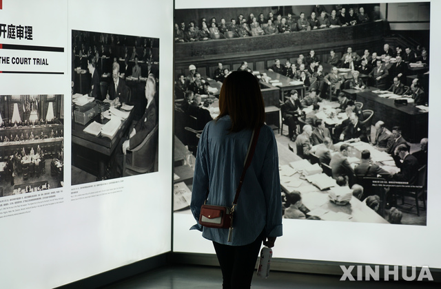 【난징(중국)= AP/뉴시스】 지난 9월 18일 난징에서 열린 난징대학살 71주기 기록사진 전시회에서 한 관람객이 전쟁후의 도쿄 일본군 전범 재판에 관한 사진을 들여다 보고 있다. 이 전시회는 2020년 3월까지 계속된다.  