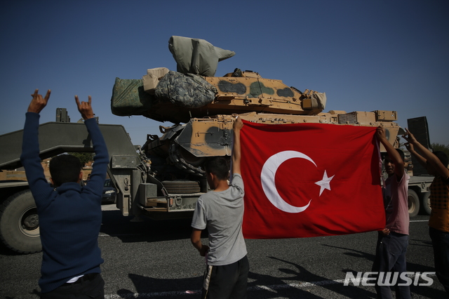  【산리우르파(터키)=AP/뉴시스】12일(현지시간) 터키-시리아 접경 지역인 터키 남동부 산리우르파주 주민들이 탱크를 싣고 시리아 방향으로 이동하는 터키군 트럭 행렬을 향해 국기를 흔들며 환영하고 있다.  미국을 비롯한 국제사회가 쿠르드족에 대한 터키의 공격 중단을 요청했지만, 시리아 국경 지역에서 30km까지 진군해 안전지대를 설치하겠다는 터키는 공격의 고삐를 늦추지 않고 있다. 2019.10.12. 