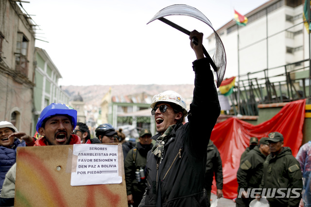 【라파스=AP/뉴시스】11일(현지시간) 볼리비아 수도 라파스 소재 대통령궁 앞에서 한 야권 시위자가 바리케이드 앞에서 방패를 치켜들고 있다. 에보 모랄레스 전 볼리비아 대통령은 전날인 10일 사임했다. 2019.11.12.