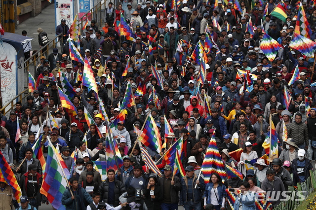 【라파스=AP/뉴시스】12일(현지시간) 볼리비아 수도 라파스에서 에보 모랄레스 전 대통령의 지지자들이 볼리비아 토착민 깃발 '위팔라'를 들고 그의 사임에 반대하는 시위를 벌이며 행진하고 있다. 볼리비아 최초의 토착민 출신 대통령이었던 모랄레스 전 대통령이 사임 이틀 만에 멕시코로 망명하면서 볼리비아에는 권력 공백과 정치적인 혼란이 가중되고 있다. 2019.11.13.
