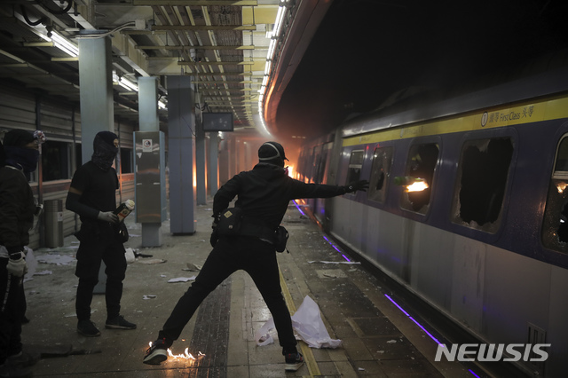 【홍콩=AP/뉴시스】13일(현지시간) 홍콩의 중문대학 MTR 역 내에서 한 시위 학생이 주정차 중인 열차를 파손하고 화염병을 던지고 있다. 시위대는 도로에 불붙은 바리케이드를 설치하고 열차를 부수거나 불을 지르는 등 대중교통을 방해해 도시 기능 마비를 시도하면서 최루탄과 물대포 등을 쏘며 저지하는 경찰과 충돌하고 있다. 시위대를 폭도로 규정한 캐리 람 행정장관은 강경 진압 방침을 굽히지 않고 있다. 2019.11.13.