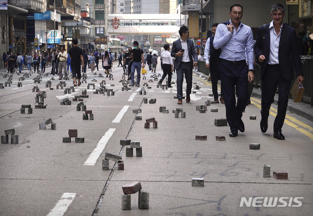 【홍콩=AP/뉴시스】도로 봉쇄를 위해 시위대가 벽돌을 설치한 홍콩 시내 도로를 14일 사람들이 지나가고 있다. 지난 11일부터 4일째 혼란이 계속되면서 홍콩이 사실상 마비 상태에 빠진 가운데 홍콩 정부가 이번 주말 통금령을 발표할 것으로 예상된다고 중국 환구시보(글로벌 타임스)가 14일 보도했다. 2019.11.14