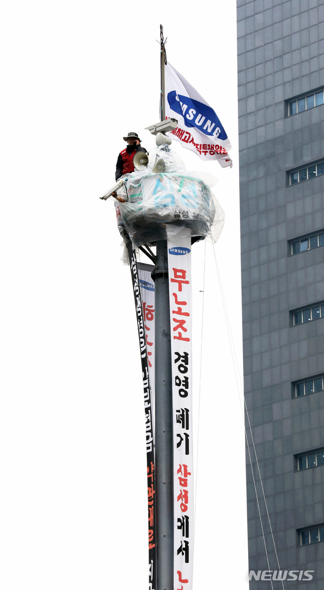 [서울=뉴시스]이윤청 기자 = 지난달 23일 오전 서울 강남구 강남역 사거리 CCTV 철탑에서 고공농성 중인 삼성 해고노동자 김용희씨가 아래에서 기자회견 중인 관계자들과 통화하고 있다. 2019.12.23. radiohead@newsis.com