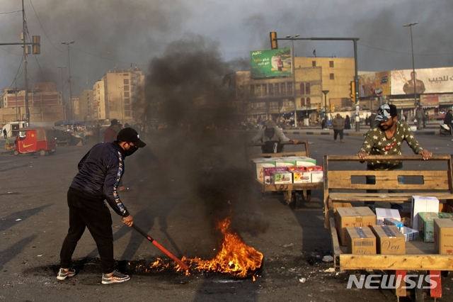 [바그다드=AP/뉴시스]8일(현지시간) 이라크 수도 바그다드의 타흐리르 광장에서 이란의 미군 기지 미사일 공격에 항의하는 시위가 열려 한 남성이 도로를 봉쇄하기 위해 불을 지르고 있다. 이란은 이날 새벽 솔레이마니 사령관을 사살한 미국의 공습에 대한 보복으로 이라크 내 두 곳의 미군 기지에 미사일 공격을 감행했다. 2020.01.08.