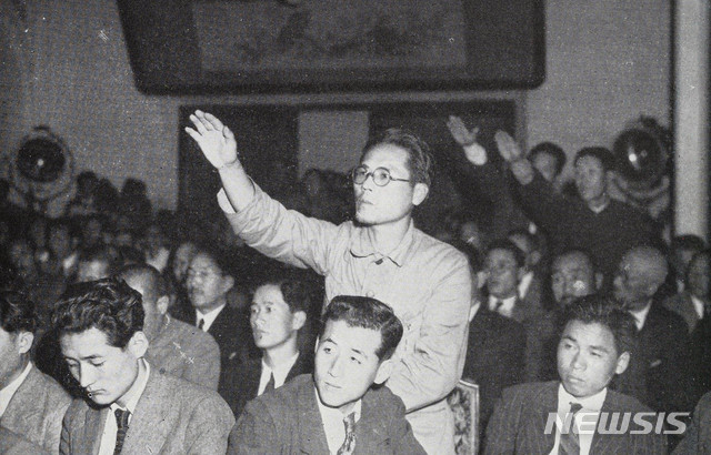 [서울=뉴시스] 1945년 9월 11일 한국 주둔 미군사령관 하지(John R. Hodge) 중장의 기자회견에 참석한 한국 기자들이 질문을 하기 위해 손을 들고 있다. (사진=미국 국립문서기록청) 2020.01.26.photo@newsis.com