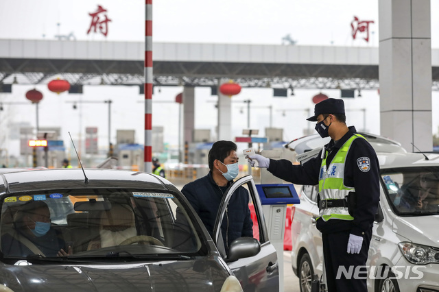 [우한=AP/뉴시스]23일(현지시간) 신종 코로나바이러스가 발발한 중국 후베이성 우한의 고속도로 톨게이트에서 경찰이 한 운전자의 체온을 검사하고 있다. 2020.01.24.  