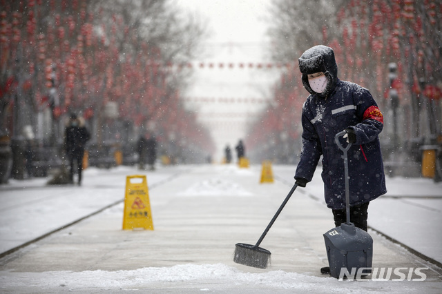 [베이징=AP/뉴시스]5일(현지시간) 눈이 내리는 중국 베이징에서 한 미화원이 마스크를 쓰고 거리의 눈을 치우고 있다. 중국에서 신종 코로나바이러스 감염증(우한 폐렴)으로 인한 사망자가 490명에 달했으며 확진자는 2만4천 명을 넘어섰다고 현지 관계자가 밝혔다. 2020.02.05.
