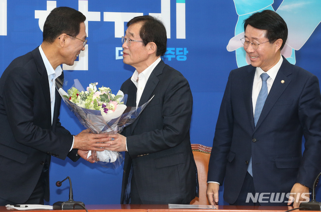 [서울=뉴시스]김명원 기자 =김주영 전 한국노총 위원장이 9일 오후 서울 여의도 국회 더불어민주당 입당식에서 이용득 의원에게 입당축하 꽃다발을 받고 있다. 오른쪽은 조정식 정책위의장. 2020.02.09. kmx1105@newsis.com