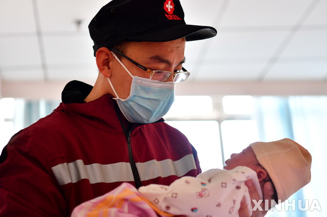[베이징=신화/뉴시스]지난 4일(현지시간) 중국 베이징에서 한 의료인이 후베이성 우한으로 신종 코로나바이러스 감염증(코로나19) 의료 지원을 떠나기 전 갓 태어난 자신의 딸을 안고 들여다보고 있다. 2020.02.12. 