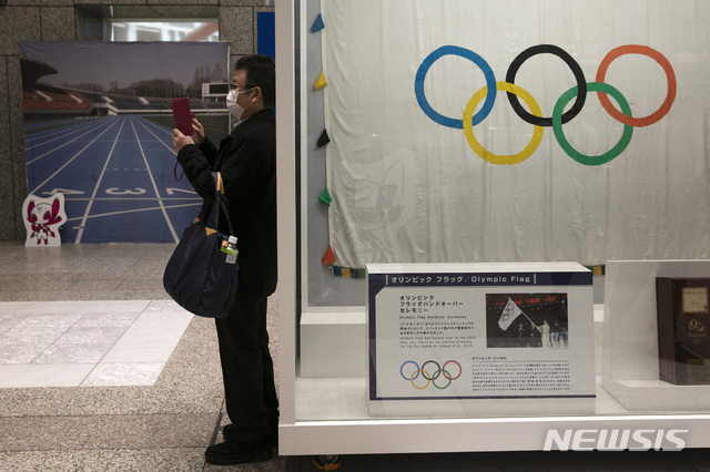 [도쿄=AP/뉴시스] 18일(현지시간) 하계 올림픽 개최를 앞둔 일본 도쿄에서 마스크를 낀 한 남성이 올림픽 마스코트 사진을 찍고 있다. 2020.02.21 