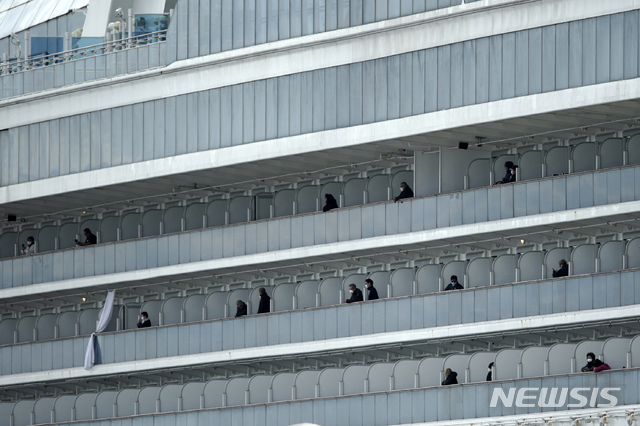 [요코하마=AP/뉴시스] 19일 일본 요코하마항에 정박 격리중인 크루즈선 다이아몬드 프린세스호에서 승객 하선이 시작된 가운데 일부 승랙들이 발코니에 나와 밖을 바라보고 있다. 2020.02.20.