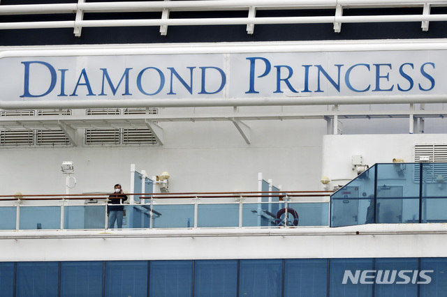 [요코하마=AP/뉴시스]일본 요코하마(橫浜)항 정박한 대형 유람선(크루즈) 다이이아몬드 프린세스호에 탑승한 한 승객이 지난 20일 마스크를 쓰고 전화를 하고 있다. 2020.02.20.