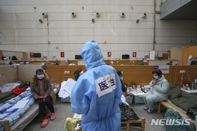  [우한=AP/뉴시스]21일(현지시간) 중국 후베이성 우한의 타즈후 체육센터에 마련된 임시 병원에서 한 의료 종사자가 신종 코로나바이러스 감염증(코로나19) 환자들을 진료하고 있다. 중국 국가위생건강위원회는 22일 오전 0시 기준 코로나19 사망자가 총 2345명, 확진자는 총 7만6288명이라고 공식 발표했다. 2020.02.22. 