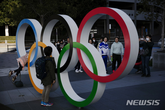 [도쿄=AP/뉴시스] 23일(현지시간) 일본 도쿄에 설치된 올림픽 오륜기 조형물 앞에서 사람들이 줄을 지어 기념사진을 촬영하고 있다. 2020.2.26.