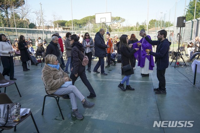 [로마=AP/뉴시스] 8일 이탈리아 로마에서 한 신부가 사순절 두 번째 일요 미사를 코로나19 저지 정부 방침에 따라 축구장 야외에서 집전하면서 신자들에게 영성체를 주고 있다. 이날 북부에 이동금지의 봉쇄령이 내려졌다. 2020. 3. 8. 