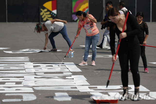 [ 멕시코시티= AP/뉴시스] 여성에 대한 폭력과 살인으로 살해된 희생자들의 이름을 시내 광장의 아스팔트 위에 페인트로 쓰고 있는 멕시코 여성시위대.  