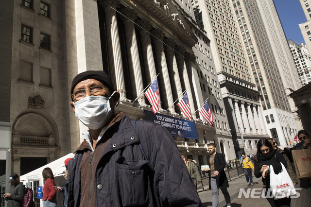 A man wears a mask as he passes the New York Stock Exchange, Monday, March 9, 2020. The dizzying action in financial markets escalated Monday as stocks moved closer to a bear market and oil prices fell the most since 2008. (AP Photo/Mark Lennihan)