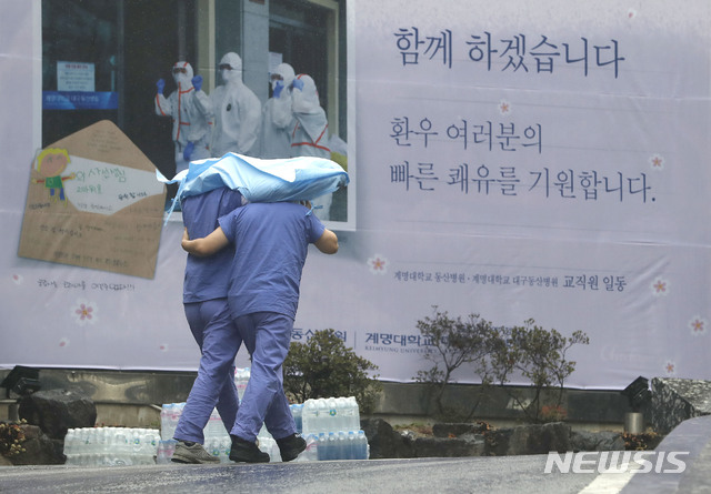 [대구=뉴시스] 최동준 기자 = 의료진들이 10일 대구 중구 계명대학교 동산의료원에서 의료복을 함께 쓰고 비를 피해 이동하고 있다. 2020.03.10.  photocdj@newsis.com