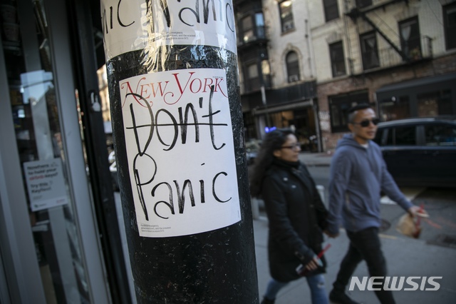 [뉴욕=AP/뉴시스]지난 15일 미국 뉴욕에서 행인들이 '패닉에 빠지지 말라(Don't panic)'는 글이 붙은 기둥을 지나고 있다. 글의 'Don't' 부분에 줄이 그어져 있다. 2020.03.18.