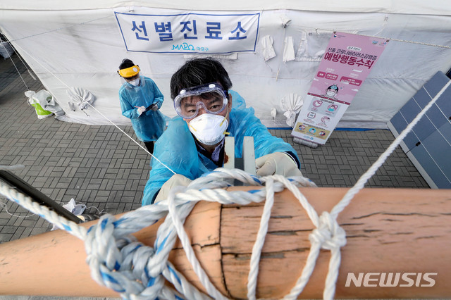 [서울=뉴시스]김병문 기자 = 선별진료소 의료진이 18일 오후 서울 마포구 보건소 선별진료소에서 내일 예보된 강풍에 대비해 끈으로 고정하고 있다. 2020.03.18.  dadazon@newsis.com