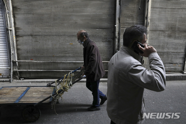 In this Tuesday, March 17, 2020, photo, a man wearing a face mask to help protect against the new coronavirus, pushes his cart past closed shops of Tehran&#039;s Grand Bazaar, Iran. The new coronavirus ravaging Iran is cutting into celebrations marking the Persian New Year, known as Nowruz. (AP Photo/Vahid Salemi)