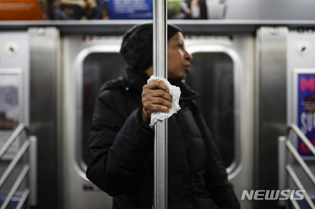 [뉴욕=AP/뉴시스]뉴욕 지하철에서 지난 19일 한 여성이 객차 내 손잡이를 휴지로 감싸 쥐고 있다. 뉴욕은 신종 코로나바이러스 감염증(코로나19) 미국 내 최대 확산지다. 2020.03.24. 