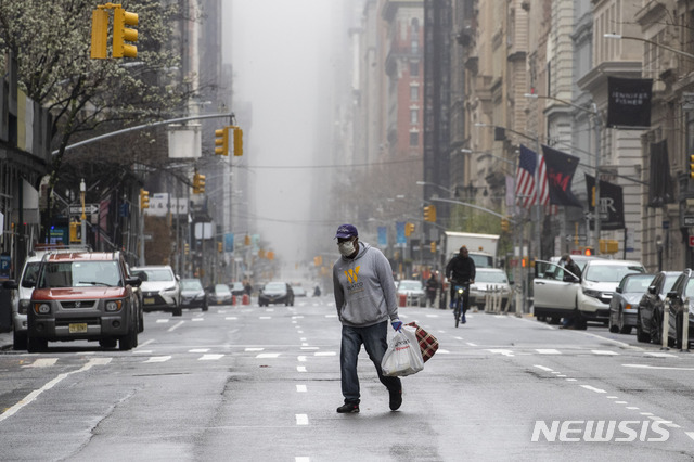 [뉴욕=AP/뉴시스]29일 뉴욕 맨해튼에서 한 남성이 마스크를 쓴 채 거리를 걷고 있다. 워싱턴포스트(WP)는 30일(현지시간) 미 질병통제예방센터(CDC)가 공공장소에서의 천 마스크 착용을 권고하는 지침을 마련 중이라고 보도했다. 2020.03.31.