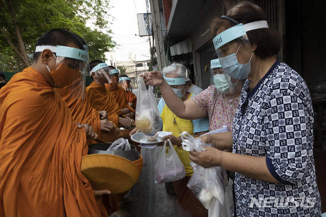 [방콕=AP/뉴시스]31일(현지시간) 신종 코로나바이러스 감염증 예방을 위해 마스크와 얼굴 가리개를 한 태국 승려들이 방콕에서 신자들로부터 시주 받고 있다. 2020.03.31. 
