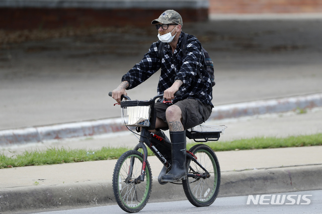 [댈러스=AP/뉴시스]31일(현지시간) 텍사스 댈러스에서 한 남성이 마스크를 착용한 채 자전거를 타고 있다. 미 보건 당국은 신종 코로나바이러스 감염증(코로나19) 대량 확산 이후 뒤늦게 일반 대중에 대한 마스크 착용 권고를 검토 중인 것으로 알려졌다. 2020.03.31. 