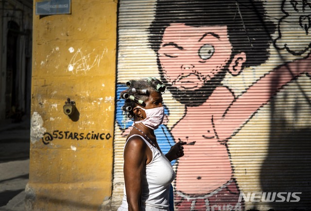 [아바나=AP/뉴시스]지난달 31일(현지시간) 쿠바 수도 아바나에서 신종 코로나바이러스 감염증 확산 예방을 위해 마스크를 쓴 한 여성이 거리 벽화 앞을 지나고 있다. 쿠바 정부는 집 밖에서는 누구라도 마스크를 착용하라고 권고하고 있다. 2020.04.01. 