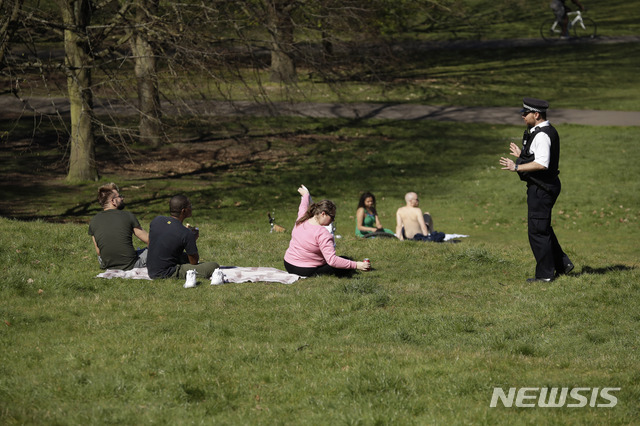 [런던=AP/뉴시스] 5일 영국 수도 그린위치 공원에서 화창한 봄날씨에 가족 나들이 나왔던 사람들에게 경찰이 다가와 금지되어 있으니 그만 집으로 들어가도록 말하고 있다. 코로나 19 대책의 사회적 거리두기 때문이다. 2020. 4. 5 